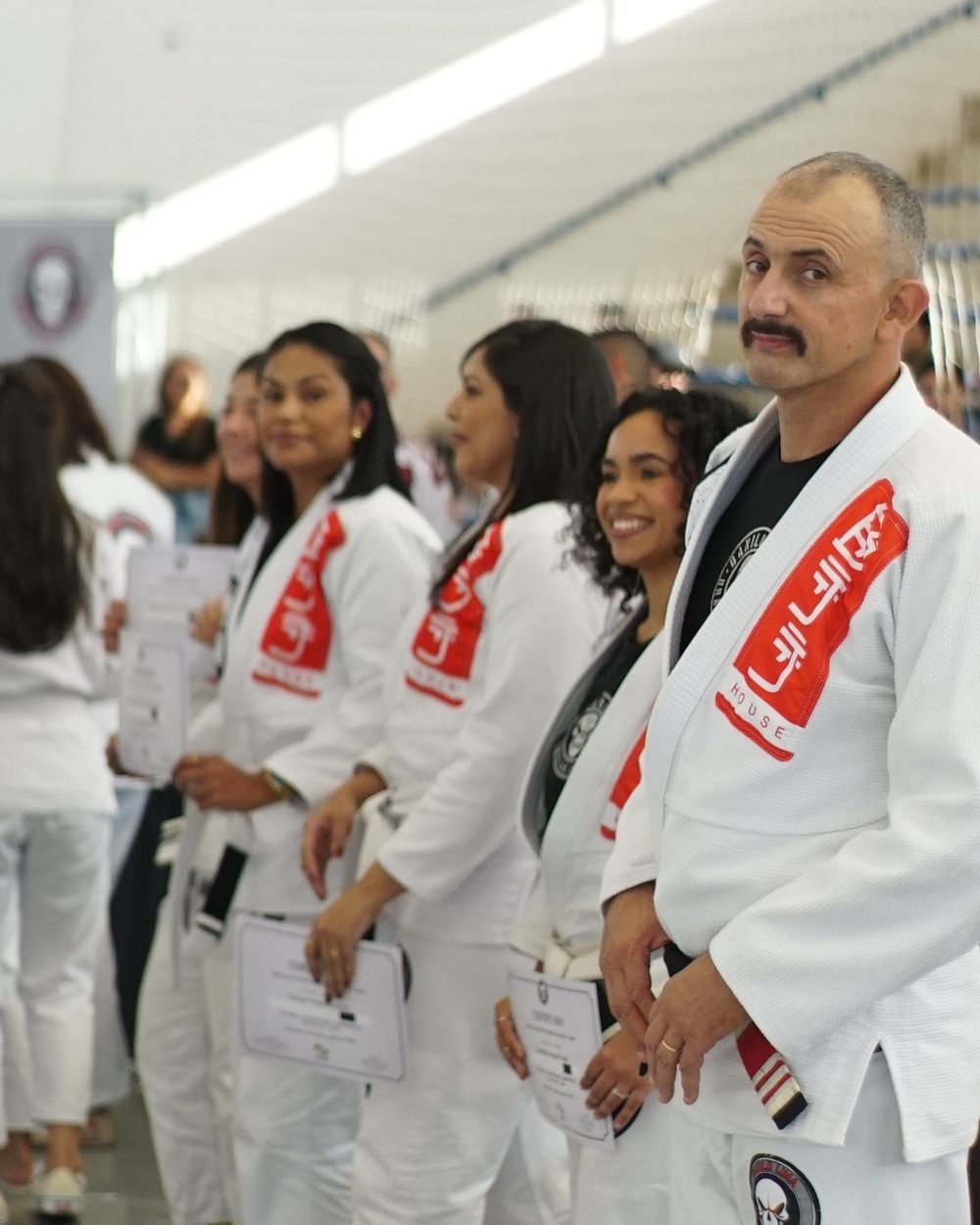 Everton Rodrigues de kimono branco em uma graduação da BJJ House, ao lado de alunos